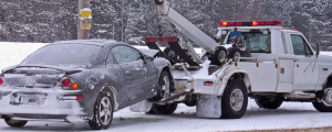Tow truck towing a car from the side of the word in winter